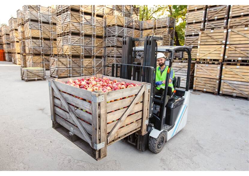 Heftruck temidden van grote kisten appels