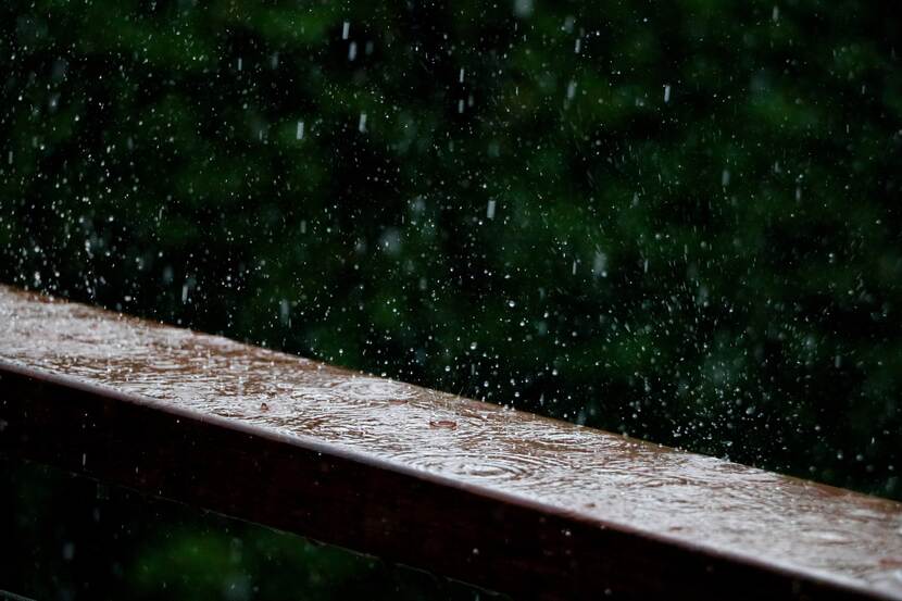 Heavy rain with droplets splashing on a wooden beam.