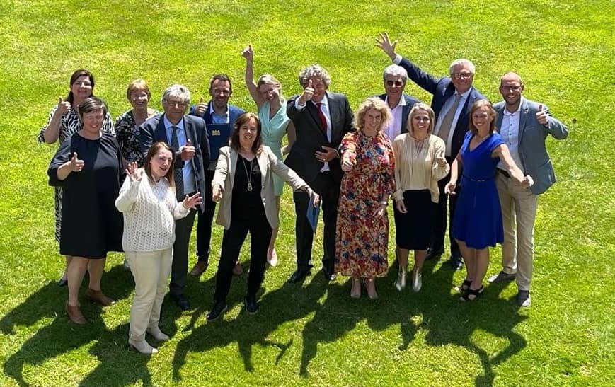 Groep van mensen op een gazon met hun handen in de lucht
