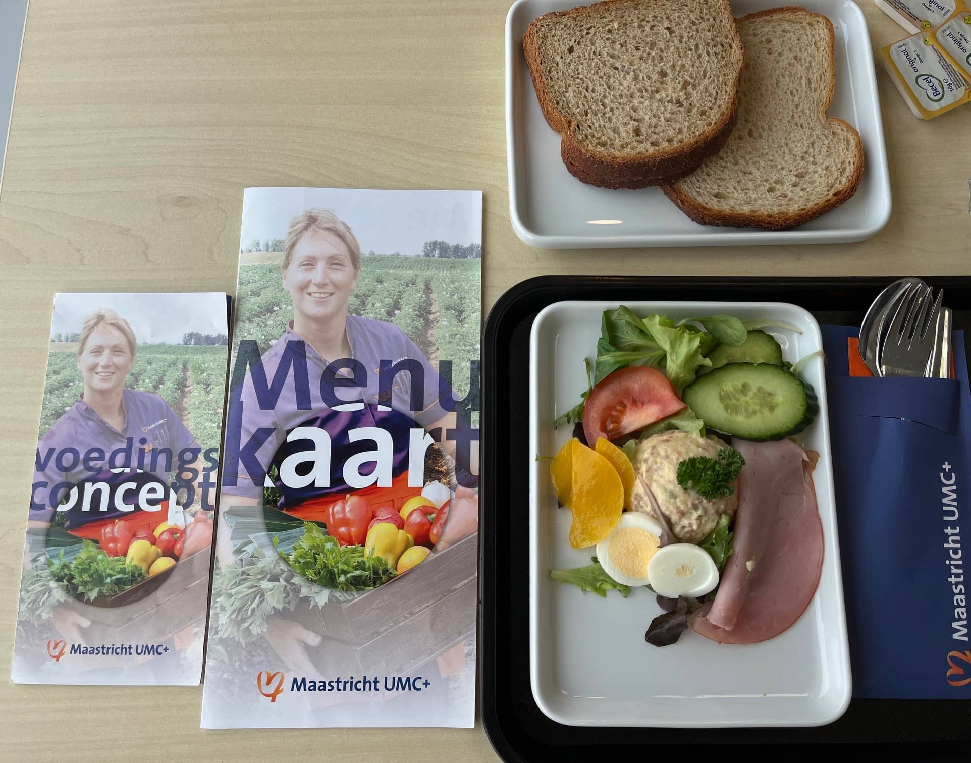 voorkant van de lunchkaart van het ziekenhuis in maastricht samen met een dienblad met een eenvoudige lunch erop