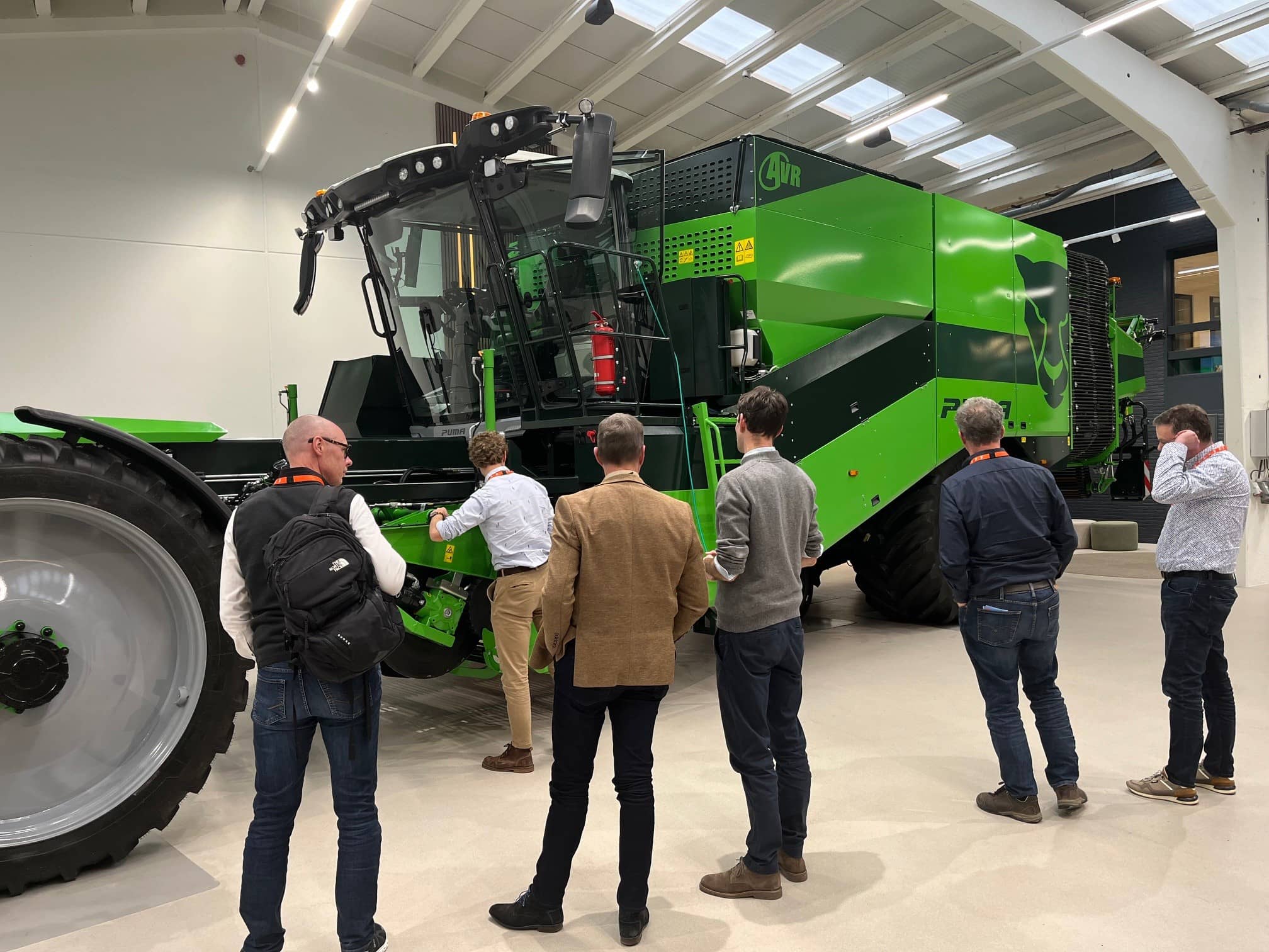 Een paar mannen kijken naar een grote machine aardappelrooier in een hal