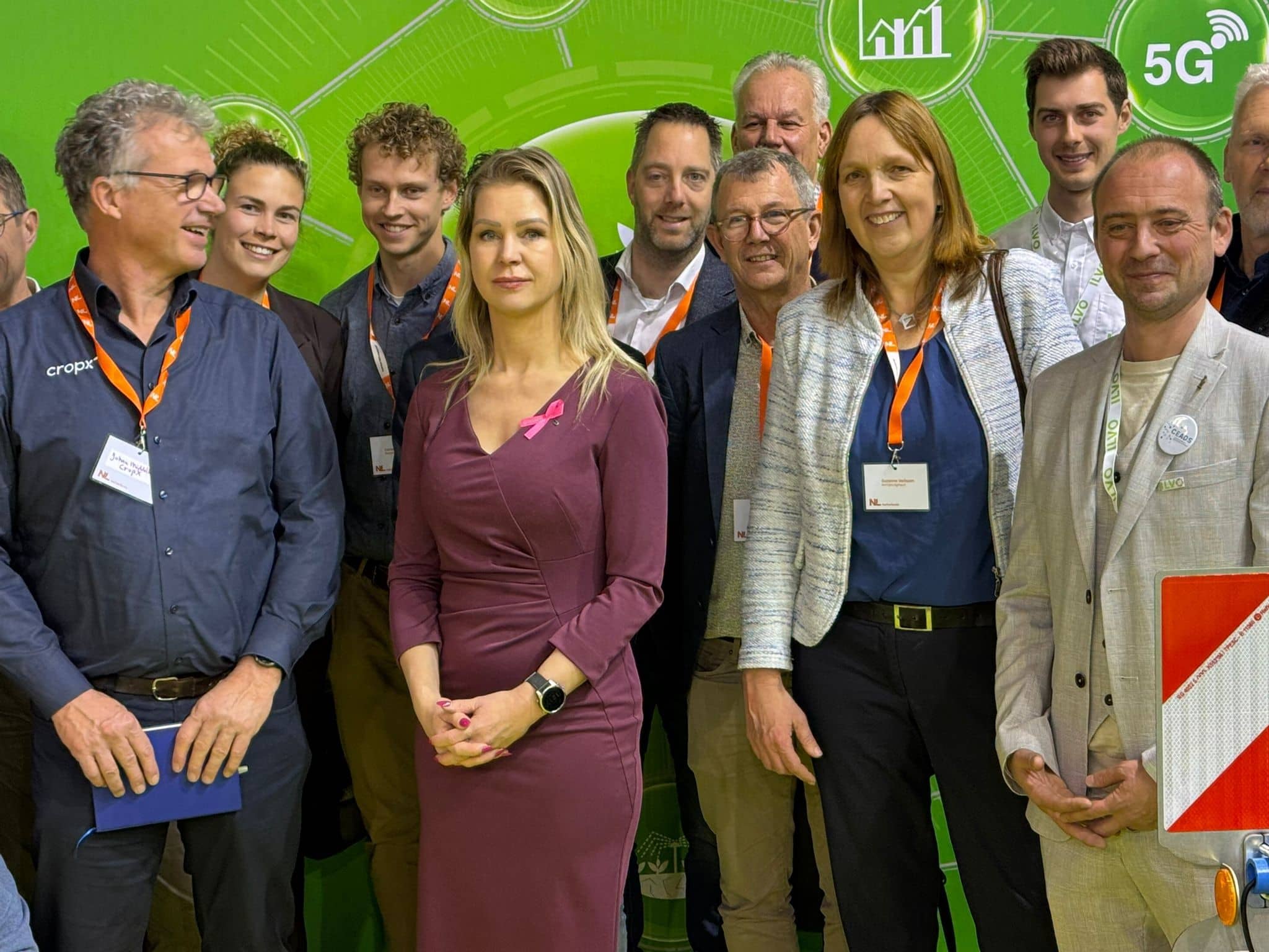 een paar mannen en vrouwen staan bij elkaar in een groep rond minister Wiersma