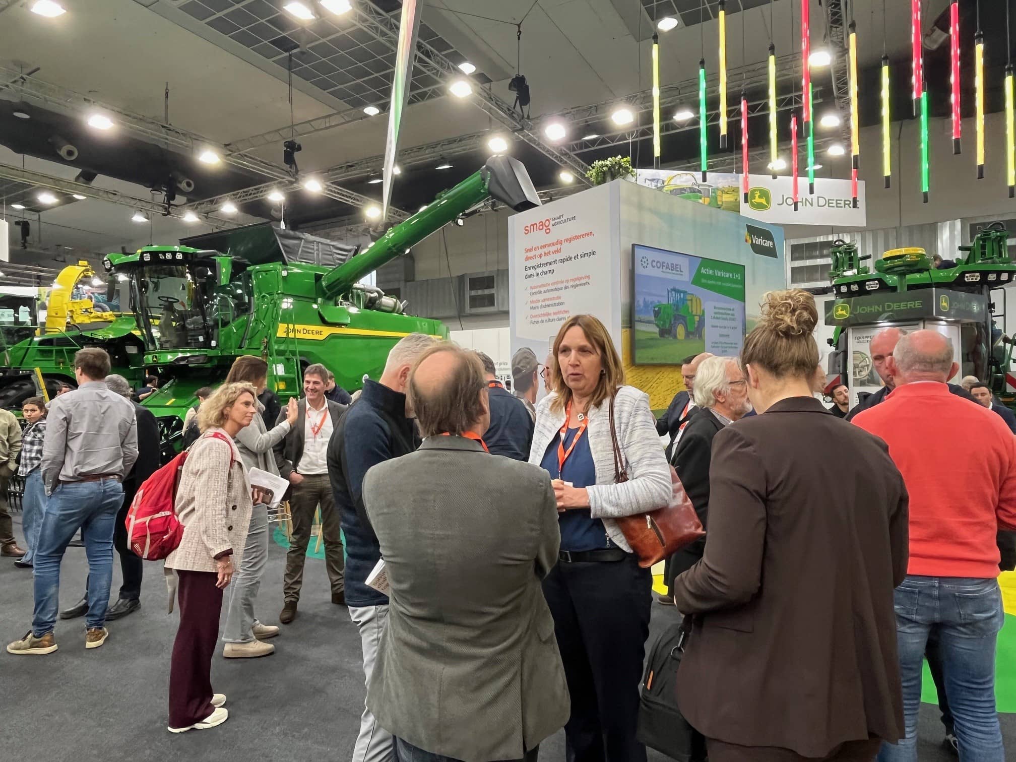 een paar mensen staan op een beurs van landbouwmachines bij een grote landbouwmachine