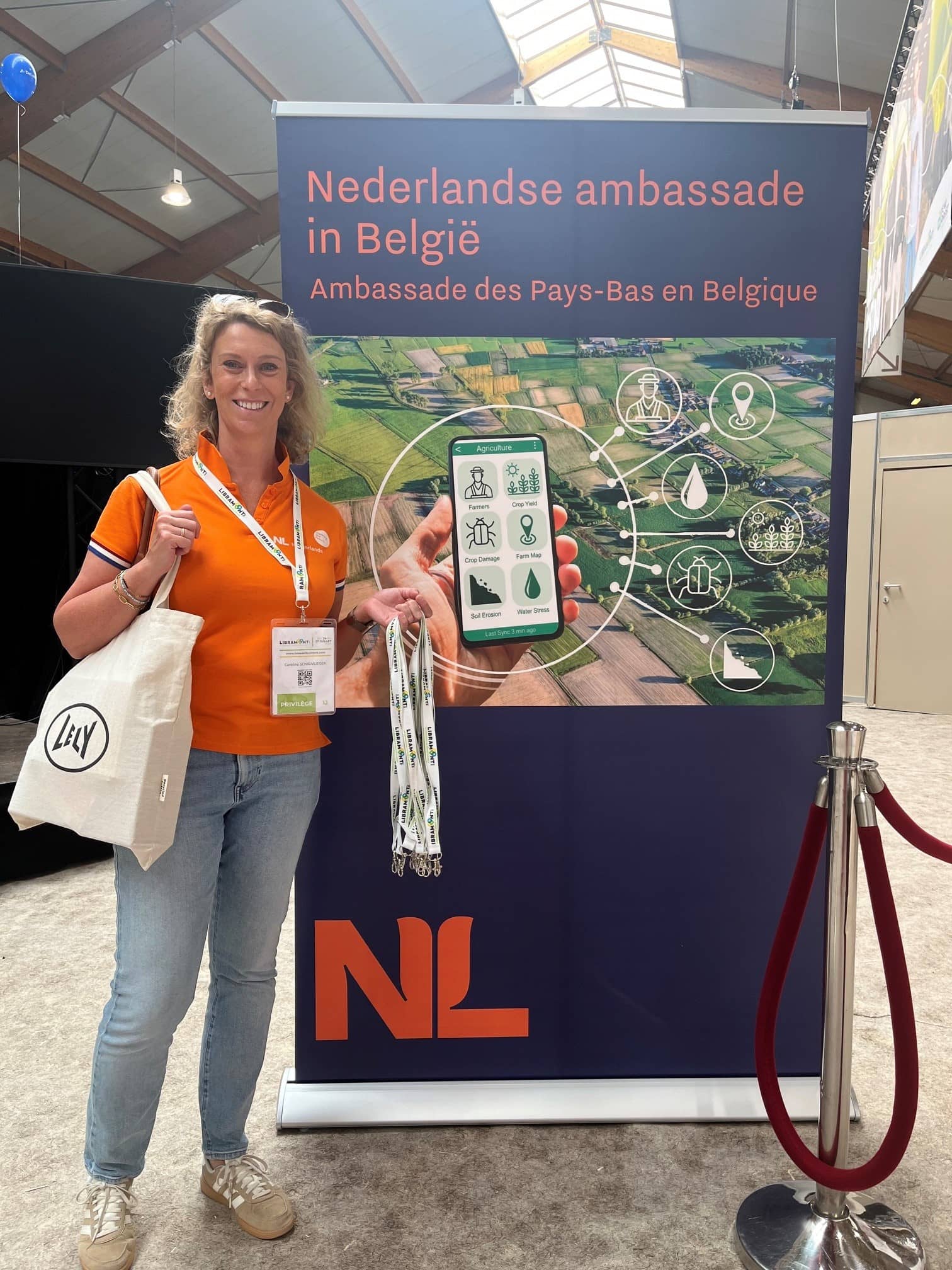 Een vrouw staat voor een banner met daarop de tekst Nederlandse Ambassade in België