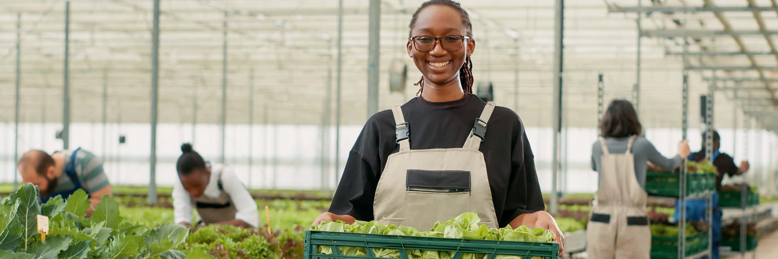 Woman smiling holding crate with lettuce