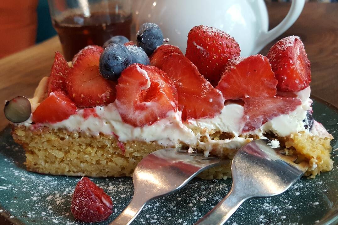 piece of cake with many fresh fruits and two forks in the cake
