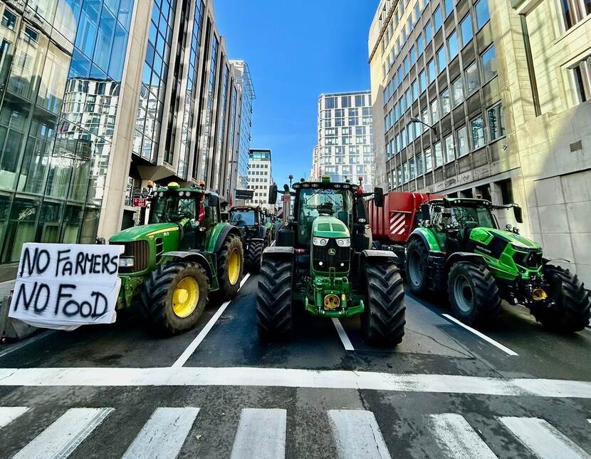 tractoren tussen hoge kantoorgebouwen in Brussel en voor een zebrapad