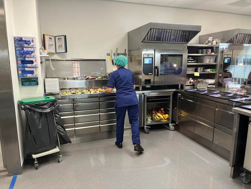 vrouw bereidt maaltijden in een professionele keuken van een ziekenhuis