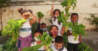 Leerlingen met hun opbrengst van één van de schooltuinen van het programma (Hortas Cariocas, 2021).