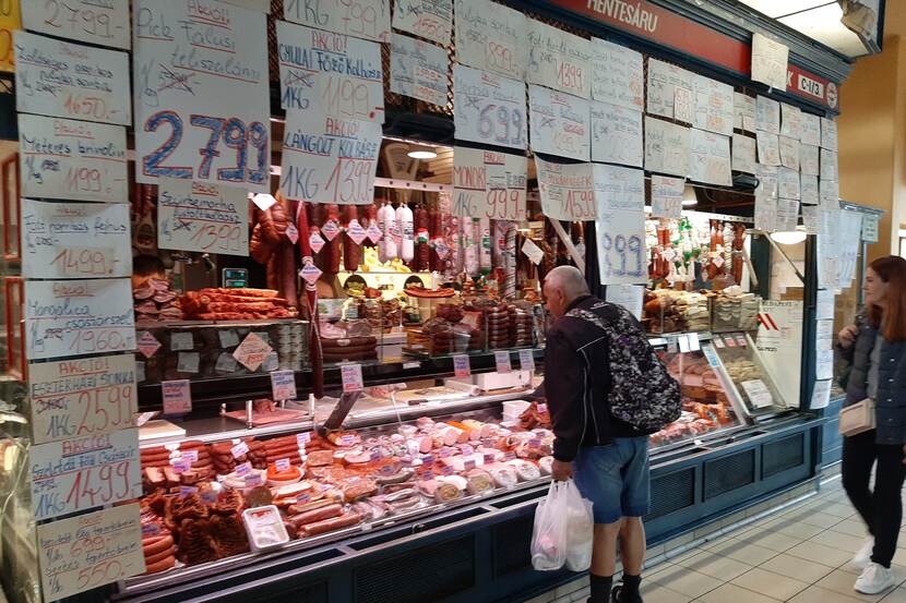 A man is browsing at the counter of a meat vendor at the Grand Market Hall in Budapest.
