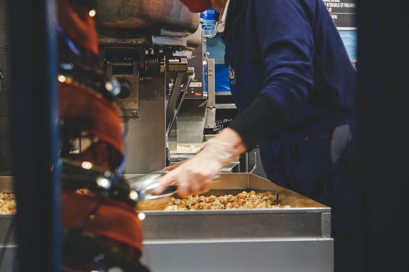 A person is working with machinery producing some sort of food