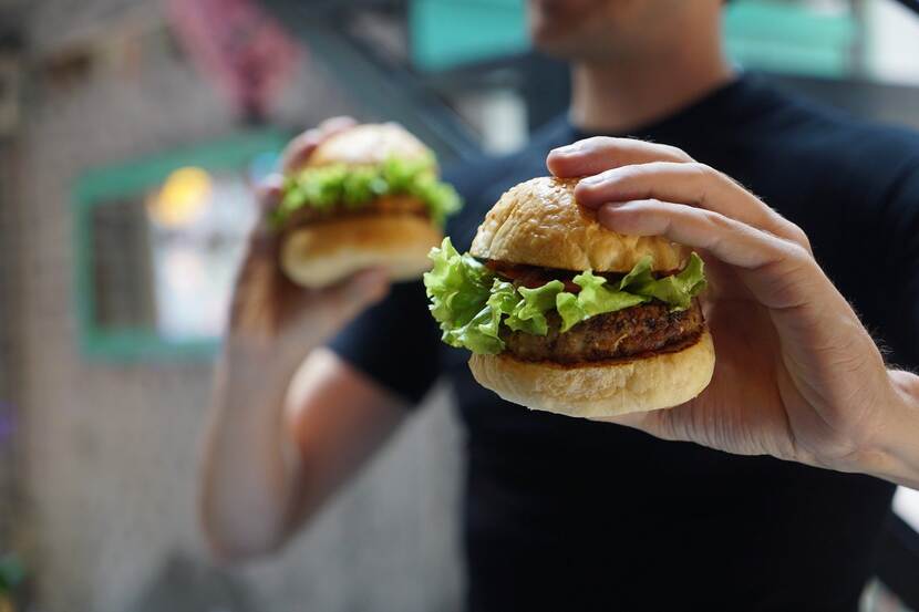 A man holding two vegan hamburgers