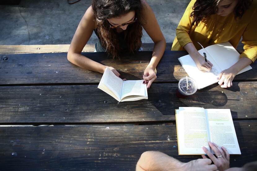 Young people sitting at a park table studying