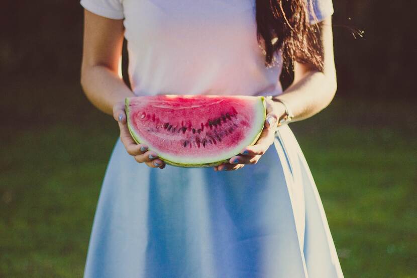 A woman holds a slice of watermelon.