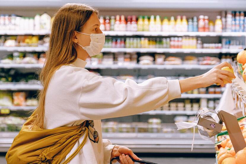 woman wearing mask and buying food at the store