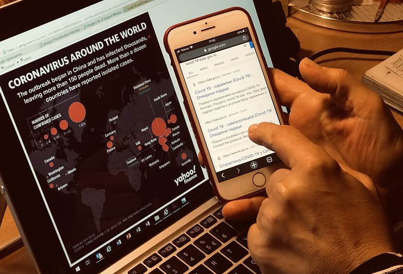 A person reading news of the coronavirus on a computer screen and a smartphone