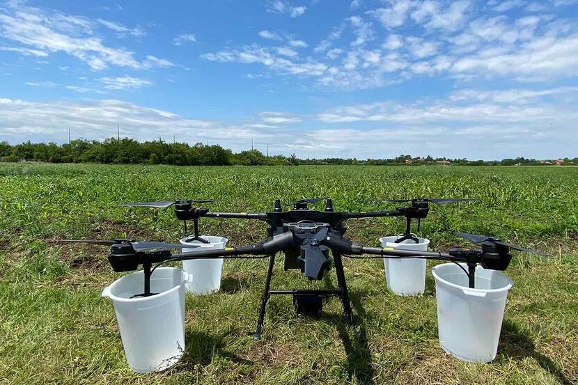 An agricultural drone can be seen placed in a green field, ready to take off.