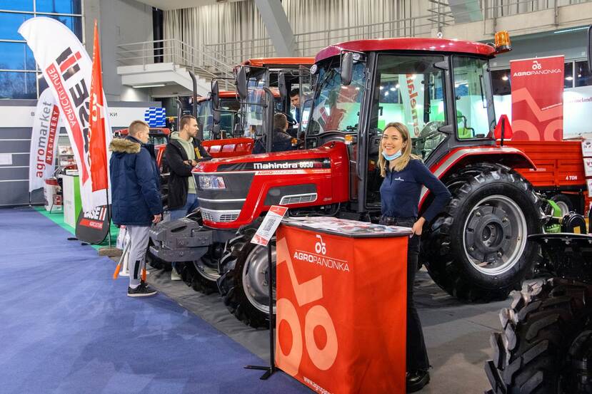 A smiling young woman is seen at a reception stand of some tractor and agro machinery company at an expo.