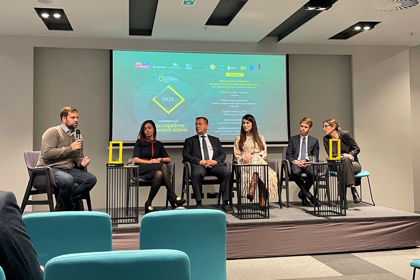 Speakers at a panel discussion at a conference organized by National Geographic Serbia. The golden rectangle logo of National Geographic is prominently featured on set.