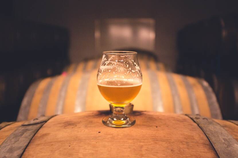 A glass of beer placed on a barrel in a cellar.