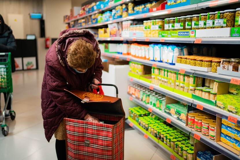 An elderly woman shopping in a grocery store.