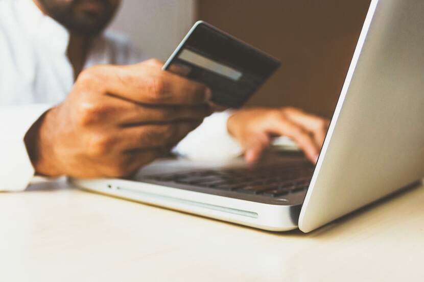Someone paying online using a laptop and a credit card.